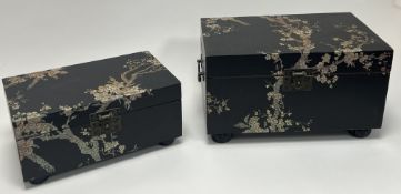 A graduated pair of modern Chinese wooden boxes, decorated with vines and blossom trees on a black