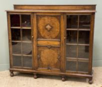 A 1930s oak and burr walnut bookcase, ledge back over carved panel central door, flanked by glazed
