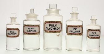 A group of five Victorian clear glass apothocary jars with gilt and gilt verre eglomise labels, in