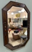 A 20thc carved oak Arts and Crafts style octagonol bevel edge mirror with beaded decoration to