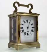 A brass four glass table clock with white enamel dial and roman numerals sticking on a gong with