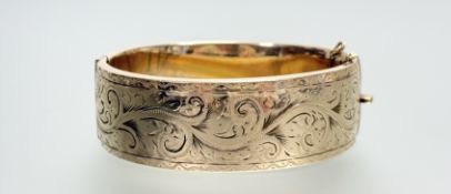 A 9ct metal core engraved, stiff-hinged bangle with clip fastening: d. x 7cm w. x 2cm 56.3g