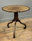 A George III tilt-top tripod table, the circular piecrust top over an incurved standard on scroll