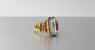 A 1970's aquamarine dress ring, the elongated rectangular-cut stone claw set on bark-textured