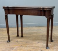 A George II mahogany and oak foldover games table, c. 1750, the lobed top opening to an oak