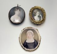 A group of three portrait miniatures, two early 19th century, each oval, on ivory: the first of a
