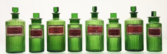 A group of eight 19th century fluted green glass apothecary jars, each with red and gilt verre