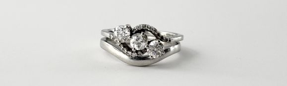 A three-stone diamond crossover ring, the uniform old mine-cut stones claw set between shoulders