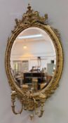 A 19th century oval gilt-composition girandole mirror, in the Rococo Revival taste, the plate within