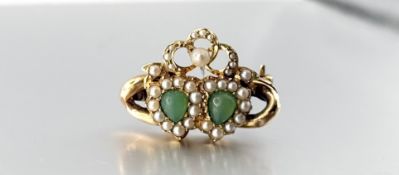 A yellow metal sweetheart brooch, set with two celadon jadeite cabochons within heart-shaped seed
