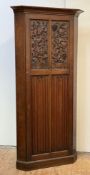 A carved oak standing corner cupboard, c. 1900, the panelled door carved with thistles, grapes and