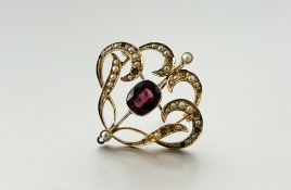 An Edwardian garnet and seed pearl brooch / pendant, centred by a cushion cut millegrain-set