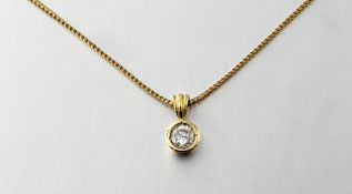 A diamond solitaire pendant. the round brilliant-cut stone in a collet setting, suspended on an 18ct