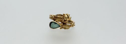 An Egyptian yellow metal ring set with a pear-cut emerald, in a fruit and leaf cast setting, the
