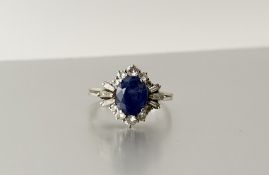 A sapphire and diamond cluster ring, the central oval-cut sapphire within a sunburst setting of