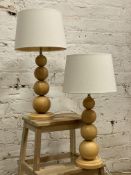 A pair of Laura Ashley oak table lamps, of graduated bobbin form with cream shade and a circular