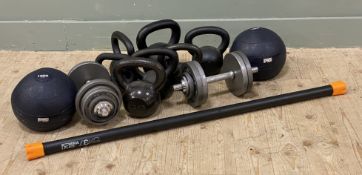 An assorted collection of dumbbells, including a Mira Fit 8kg bar, two 15kg F45 medicine balls,