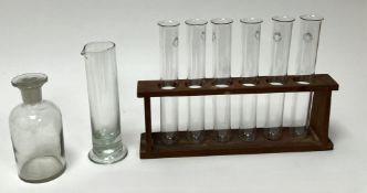 A collection of six Pyrex scientific/medical test tubes held in a wooden stand, together with a