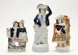 A group of three Staffordshire figures comprising, a boy and girl flatback figure both holding