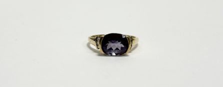 A 9ct gold oval facet cut tanzanite ring of purplish blue colour approximately 1.5ct set three round
