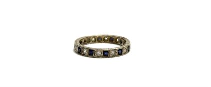 A white metal eternity ring set twelve cushion cut sapphire coloured stones separated by a round cut