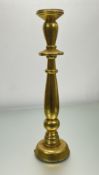 A singular turned wooden candlestick of baluster form, finished in gilt paint, with a stepped
