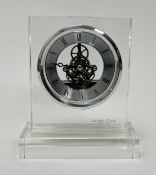 A modern London Clocks Company skeleton mantel clock within a clear acrylic case with a chrome