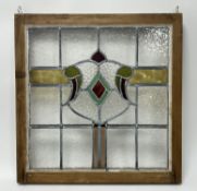 A vintage Victorian-style framed stained glass window panel with red, yellow, and green accents held