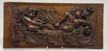 A 19thc Oak carved relief panel, of two cherubs riding an animal, one cherub with a horn in hand. (