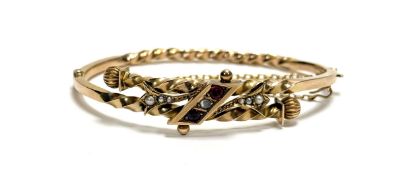 An Edwardian yellow metal cross over stiff hinged bracelet with rope twist and fluted ball terminals