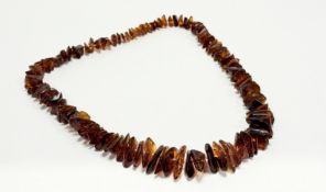 A dark treakle graduated thong amber necklace: l. x 30cm 81.2g