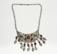 An Iranian white metal crescent shaped pendant with inset coloured glass beads and matching bead and