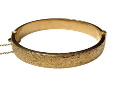18ct gold hinged bangle with engraved floral scroll decoration to one side (Birmingham 1962)