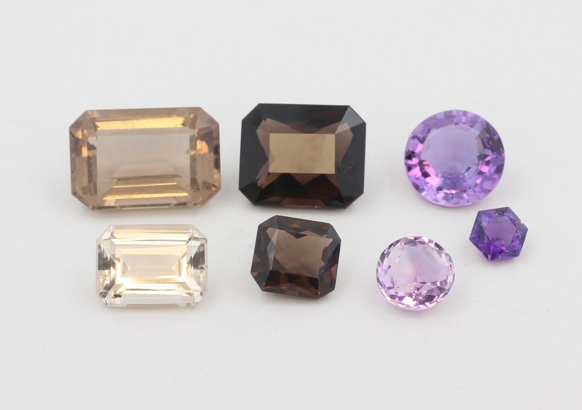 7 Schmucksteine, 3 Amethyste, D. 0,7 cm - 1,4 cm, 4 wohl Topase, D. 1,1 cm - 2,1 cm, teils leicht