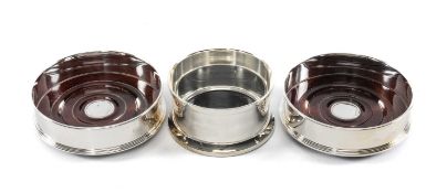 PAIR OF MILLENNIUM SILVER COASTERS with turned wooden bases, hallmarked 2000, 12.5cms (diam.); and