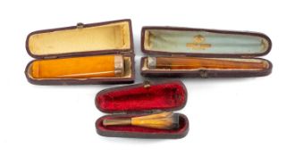 THREE CHEROOT HOLDERS, comprising amber cheroot holder with rose gold band, another with silver