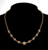 ANTIQUE YELLOW METAL & SEED PEARL NECKLACE, having nine seed pearl set flower heads, 40.5cms long,