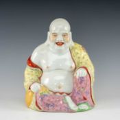 CHINESE FAMILLE ROSE PORCELAIN FIGURE OF BUDAI, seated holding a rosary and the neck of a sack,