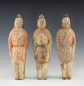 THREE CHINESE UNGLAZED POTTERY FIGURES, probably Northern Qi Dynasty (550-577 A.D.) dressed in loose