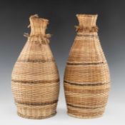 TWO WOVEN RATTAN FISH TRAPS, Papua New Guinea, with fringes around the narrow necks, woven in two
