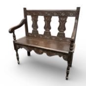 GOTHIC STYLE OAK SETTLE, with carved triple-panel splat back, open arms, solid seat, and turned