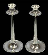 PAIR OF GEORGE V ARTS & CRAFTS SILVER CANDLESTICKS, circular loaded bases, tapered columns, wide