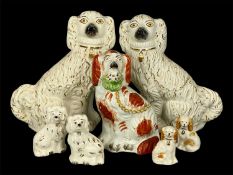 STAFFORDSHIRE DOGS, 19th century and later, including a seated single holding basket of flowers in
