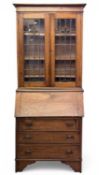 OAK BUREAU BOOKCASE of narrow form, circa 1900, with leaded glazed upper doors, drop-down middle,