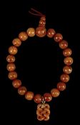 CHINESE RED JADEITE BEAD BRACELET, with eternity knot charm Provenance: private collection Ynys Môn