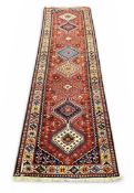 PERSIAN YALAMEH WOOL RUNNER, red ground with centre column of geometric lozenges, within a geometric