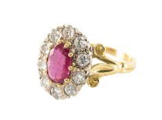 18CT GOLD RUBY & DIAMOND CLUSTER RING, the central claw-set oval ruby (7 x 4mms) within border of