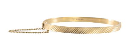 9CT GOLD HINGED BANGLE with chevron engraved decoration, cuff size 58mms, with safety chain, 10.2g