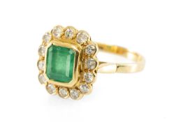 YELLOW METAL EMERALD & DIAMOND CLUSTER RING, the central step-cut bezel set emerald measuring 7 x