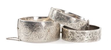 THREE HINGED SILVER BANGLES, each with scroll engraved decoration to one side, 93g gross Provenance: